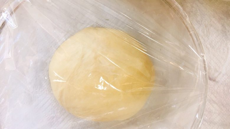 金黄诱人的椰蓉扭扭条面包,取出面团揉圆，盖上保鲜膜室温发酵一小时。