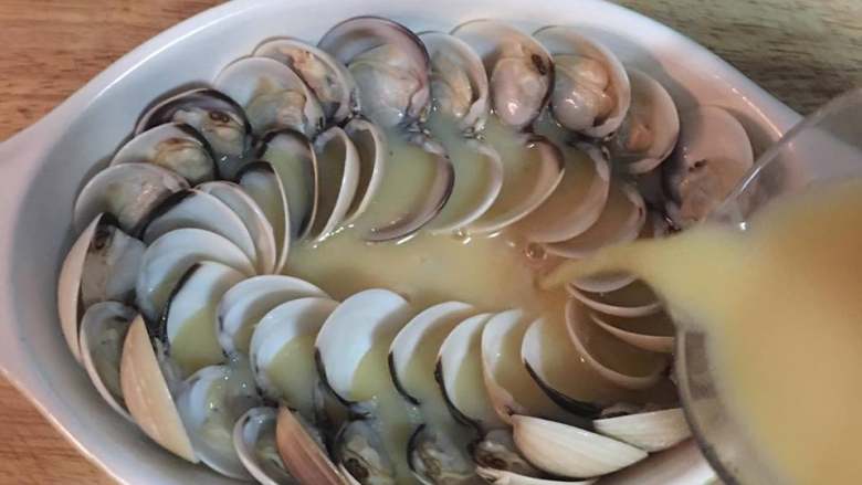 蛤蜊嫩蒸蛋,接着将滤过的蛋液倒入排好蛤蜊的蒸蛋容器中。