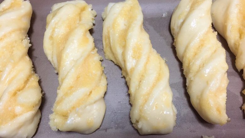 早餐+奶香椰蓉棒,发酵至1.5-2倍大后，取出两个烤盘。在椰蓉条表面刷上一层蛋液。烤箱提前预热160度。