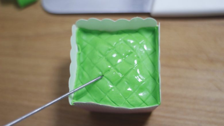 零基础纸杯翻糖蛋糕,压好格子的糖皮覆盖在蛋糕上面，点两滴植物油润一下表面，不明显的网格线在用工具压深一点。