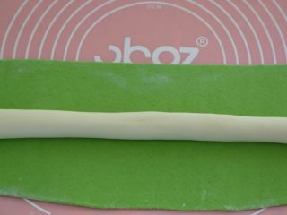 绿色美食+翡翠白菜水饺,翡翠面团擀成长片，白色面团搓成长条，然后放到长片上。