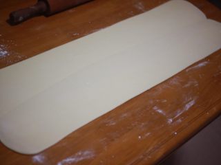 丹麦手撕吐司,用走锤顺着接缝的方向擀开，擀至0.5cm厚左右，擀开的时候要注意用力均匀，使黄油分布均匀，台面上要撒粉防粘