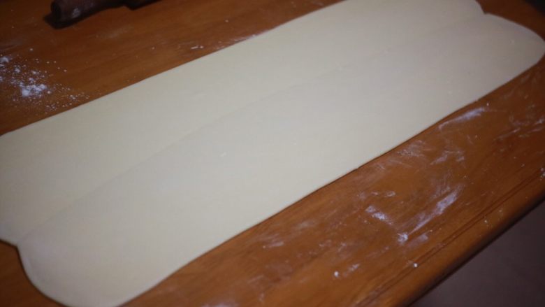 丹麦手撕吐司,用走锤顺着接缝的方向擀开，擀至0.5cm厚左右，擀开的时候要注意用力均匀，使黄油分布均匀，台面上要撒粉防粘