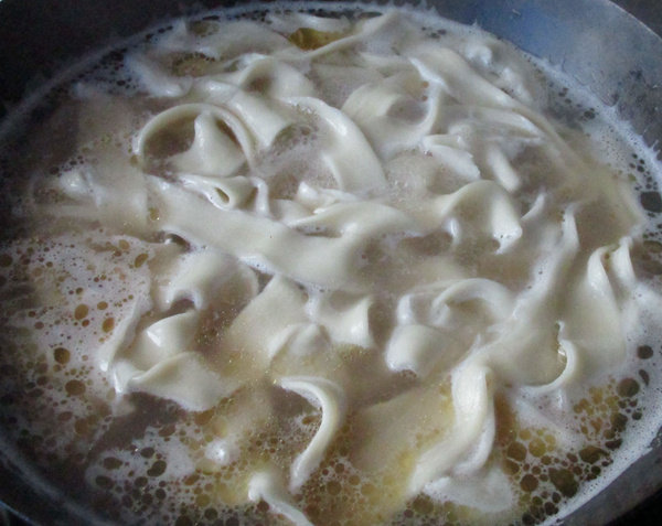 牛骨汤烩面,把和好 的面胚拉长后从压痕处分成两根，入锅煮熟