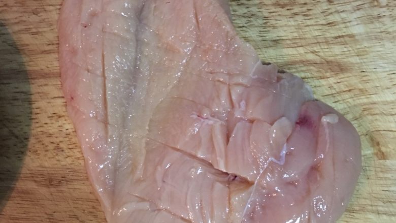 剁椒蒸土豆鸡胸,接着在鸡胸的两面都划出刀痕，方便入味，并用少许盐均云抹在两面的肉上。