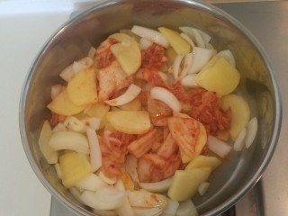 泡菜锅,炒至土豆和元葱变软后加入辣白菜继续翻炒。