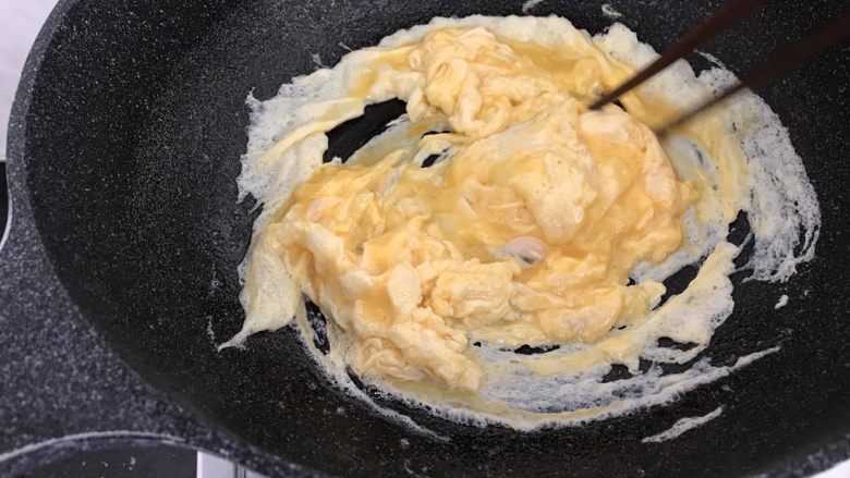 绿色美食～苦瓜炒蛋,蛋液开始凝固时，筷子顺一方向打圈，直到全部凝固（这样炒出来的蛋花比较蓬松饱满有弹性哟）