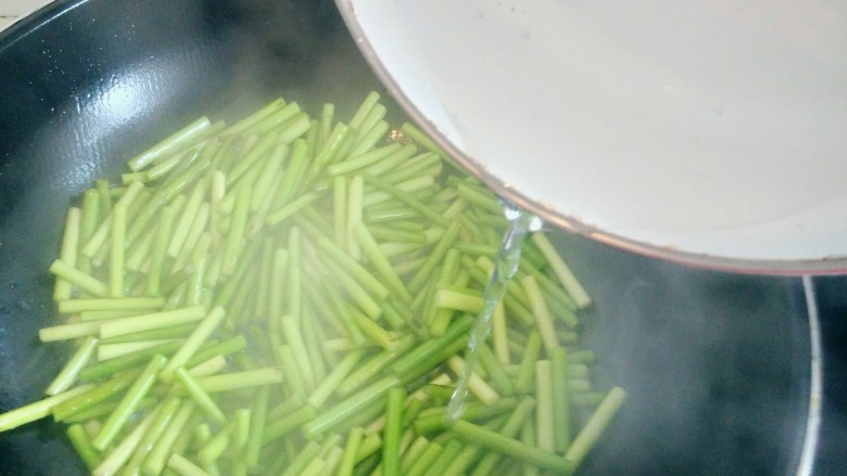 绿色美食＋蒜苔炒肉丝,下入蒜苔翻炒，待蒜苔水汽干了，倒入少许开水，继续翻炒，收干水份。