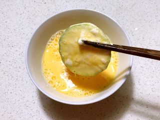 香煎西葫芦鸡蛋饼,把蘸好淀粉的西葫芦片放入鸡蛋液中，裹上一层蛋液