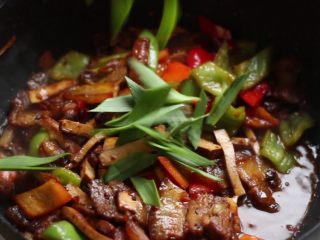 绿色美食+豆豉香干回锅肉,锅中放入青蒜段炒匀。