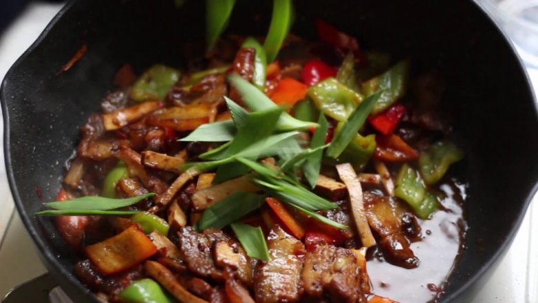 绿色美食+豆豉香干回锅肉,锅中放入青蒜段炒匀。