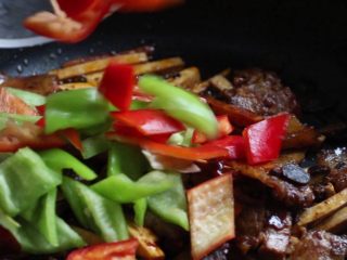 绿色美食+豆豉香干回锅肉,锅中放入青红椒片炒至断生。