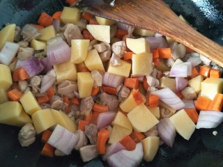 鸡肉咖喱饭,接着放入胡萝卜块，圆葱块，土豆块翻炒。