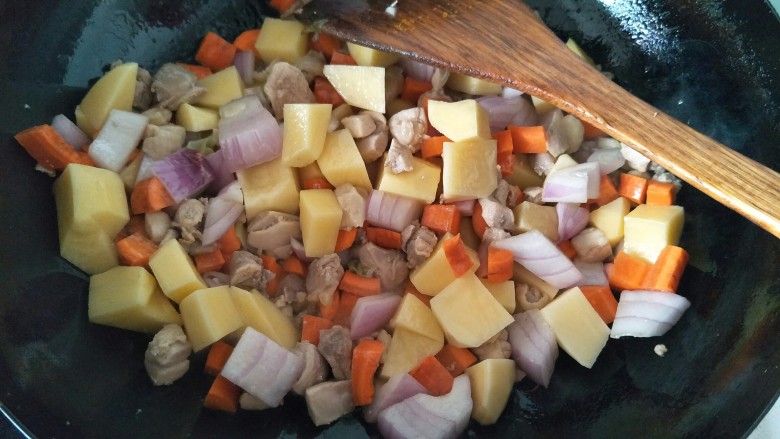 鸡肉咖喱饭,接着放入胡萝卜块，圆葱块，土豆块翻炒。