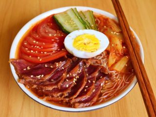 韩式荞麦冷面,把面放碗里，放入调味酱和汤包拌匀。再放入配菜摆盘即可。