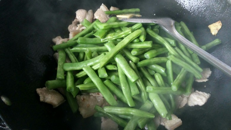 绿色美食+干锅四季豆（微辣）,倒入四季豆，放适量的盐并翻炒。