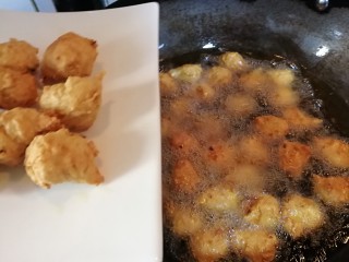芡汁豆腐,炸好的丸子漂浮在油上面。
