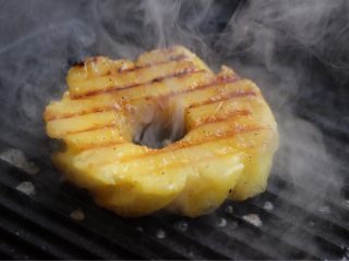 烤菠萝鸡肉汉堡,将大片的厚切菠萝放在明火加热的高温铁锅上炙烤，两面都烤一下。