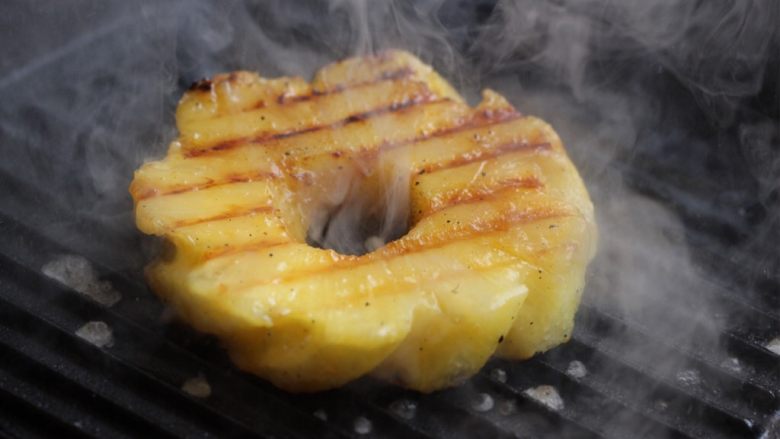 烤菠萝鸡肉汉堡,将大片的厚切菠萝放在明火加热的高温铁锅上炙烤，两面都烤一下。