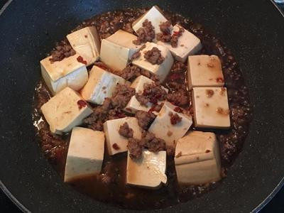 剁椒燒豆腐,放入滾水燙過的豆腐，並小心的將絞肉由鍋底往豆腐上澆淋；