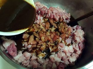 自制腊肠,将搅拌均匀的调料倒入肉块中。