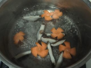 腊肠煲仔饭,锅内烧开水，放入香菇片和胡萝卜片烫半分钟，捞出沥干水分。