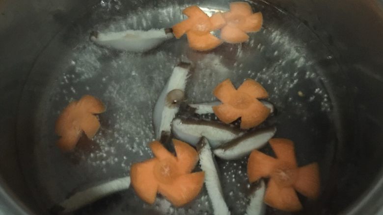 腊肠煲仔饭,锅内烧开水，放入香菇片和胡萝卜片烫半分钟，捞出沥干水分。