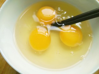 快手美味蒜黄炒鸡蛋,打入碗内，用筷子搅拌。