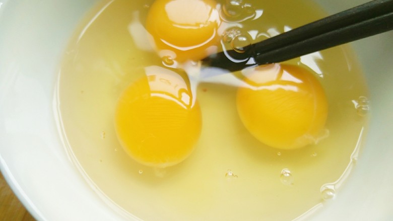 快手美味蒜黄炒鸡蛋,打入碗内，用筷子搅拌。