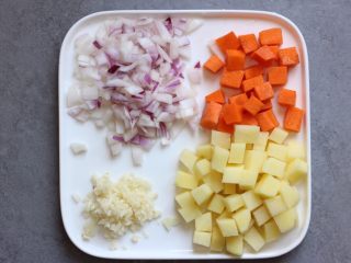 咖喱鸡翅,将胡萝卜、土豆切成小块（土豆切好放清水中，以免变色）洋葱、蒜切成丁。