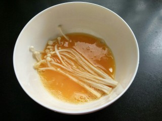 油炸金针菇,将金针菇放入鸡蛋中，裹上鸡蛋液。