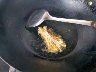 油炸金针菇,将金针菇放入锅中油炸。