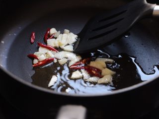 酒蒸文蛤,炒锅中小火加热加入油，四成热放入蒜和辣椒煸香。