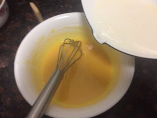 舒芙蕾乳酪蛋糕,边把热牛奶慢慢倒入蛋黄糊里边快速搅拌。