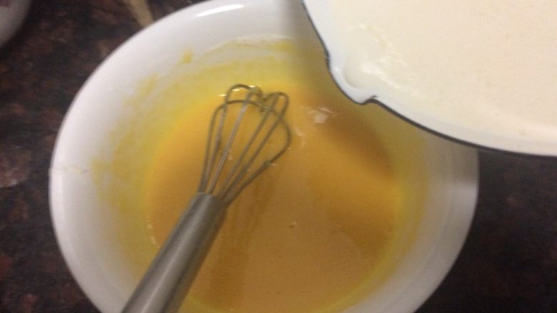 舒芙蕾乳酪蛋糕,边把热牛奶慢慢倒入蛋黄糊里边快速搅拌。