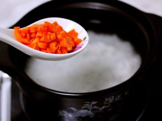 剩米饭也有春天（海鲜杂蔬粥）,砂锅里的米饭煮沸后、加入胡萝卜丁