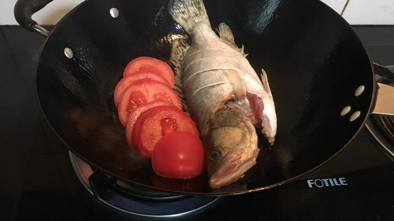 鲜掉眉毛的奶汤鳜鱼,等到晃动锅子能感受到鳜鱼自由滑动时，把它拨在一边，下番茄略炒。