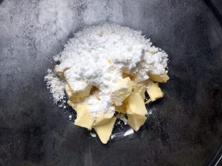 万圣节-南瓜鬼脸饼干,将糖粉全部倒入黄油中搅拌均匀，然后用打蛋器打至顺滑。