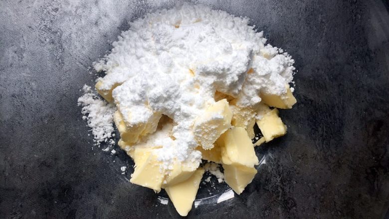 万圣节-南瓜鬼脸饼干,将糖粉全部倒入黄油中搅拌均匀，然后用打蛋器打至顺滑。