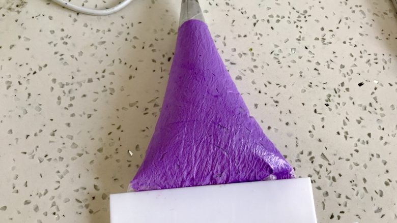 法式紫色马卡龙,用刮板挤到裱花嘴的出口处。