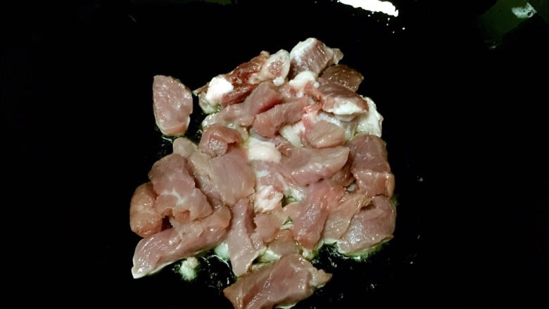 猪耳朵豆角炖肉,锅内放油烧至五成热，放入猪肉翻炒。