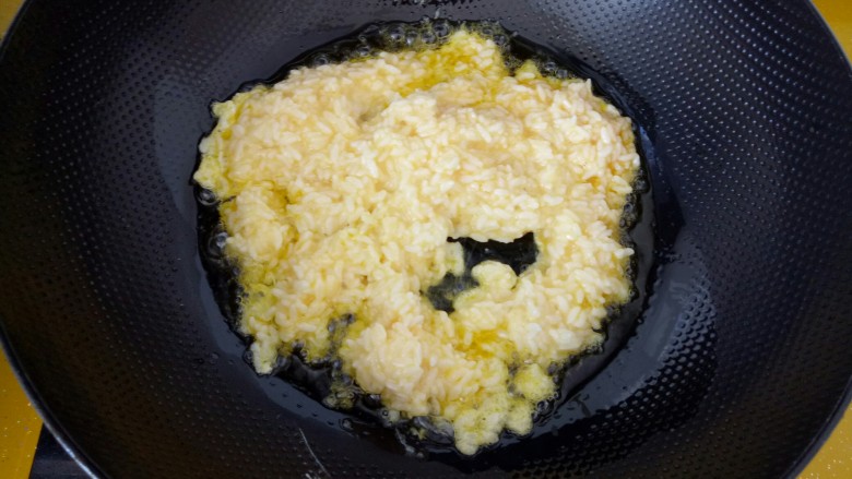 #剩米饭的百种做法#,油温到7分热时，放入浸好蛋液的米饭。翻炒。