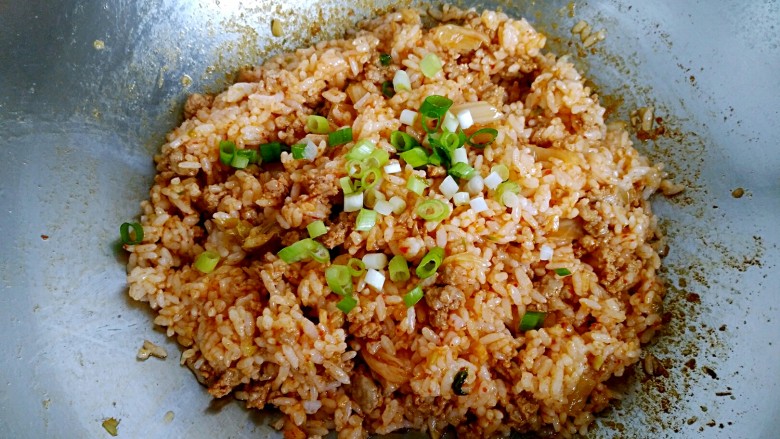 辣白菜肉末炒米饭,最后撒入剩下的葱花，翻炒均匀即可关火出锅。