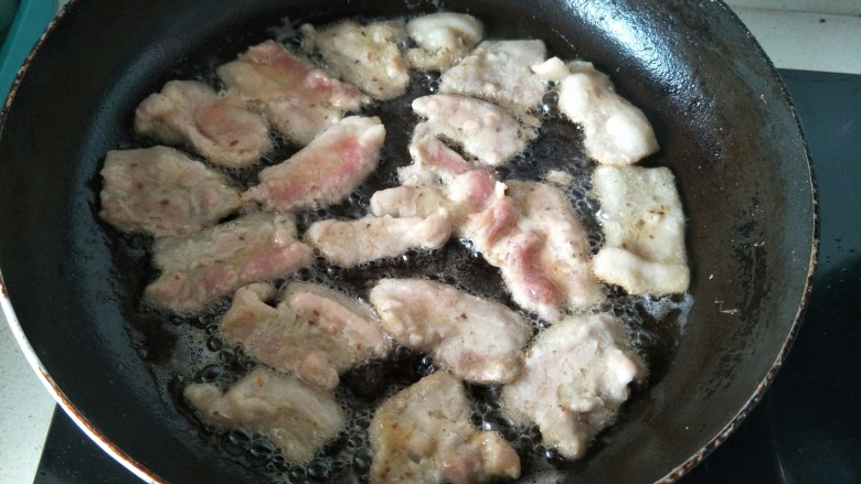 煎炸小酥肉,平底锅放油加热，用筷子夹起腌制好的肉片一片片平铺煎炸。