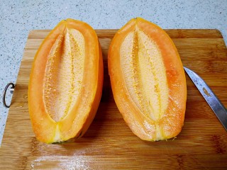 桃胶木瓜炖奶 #冬喝暖饮夏吃冰#,煮牛奶的时候来处理木瓜。把木瓜对半切开。