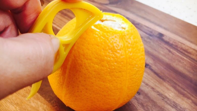 #冬喝热饮夏吃冰# 自制鲜橙汁,用剥皮器从橙子顶部起至橙子的尾部，深深的划一刀，一定多划几刀，利于剥皮。