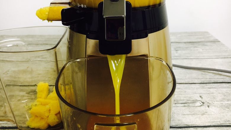 #冬喝热饮夏吃冰# 自制鲜橙汁,掀开榨汁机出汁口键，橙汁流入容器中。