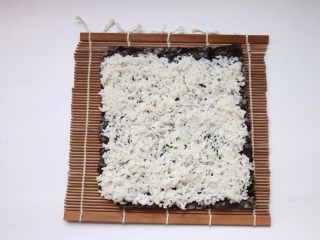 自制日式寿司,均匀铺上米饭，末尾留2厘米左右不放米饭，方便卷起来收口