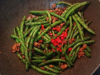 乾煸四季豆,开盖试咸度后做条整，并放入辣椒丁即可。