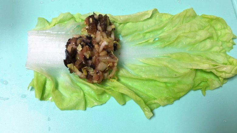 翡翠白玉猪肉卷,把白菜叶平铺在案板上，用馅料铺在菜叶子上（靠近白菜帮的那头）